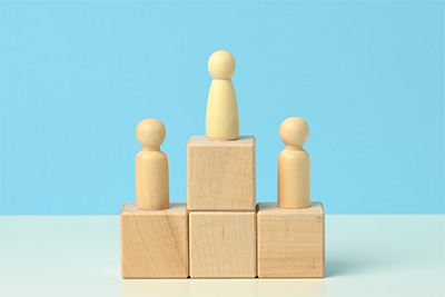 Holzfiguren auf einem Podest &ndash; symbolisiert Ranking oder Wettbewerb.